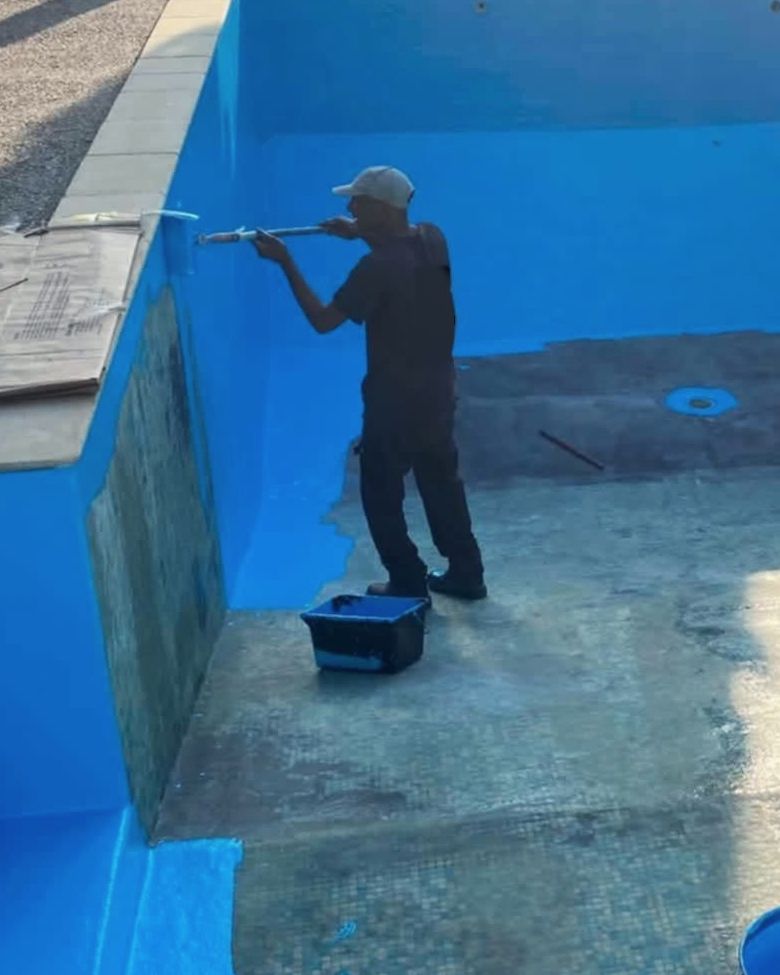 Yanis, fondateur d'Expedit Piscine, applique le revêtement polyester au rouleau